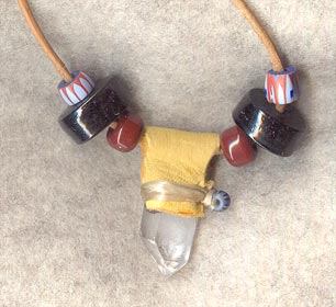 Tan buckskin wrap over Arkansas quartz crystal; accented with brown glass crow beads and antique black glass disks on 30