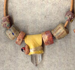 Tan buckskin wrap over Arkansas quartz crystal; accented with antique sandcast and pipestone beads on 30
